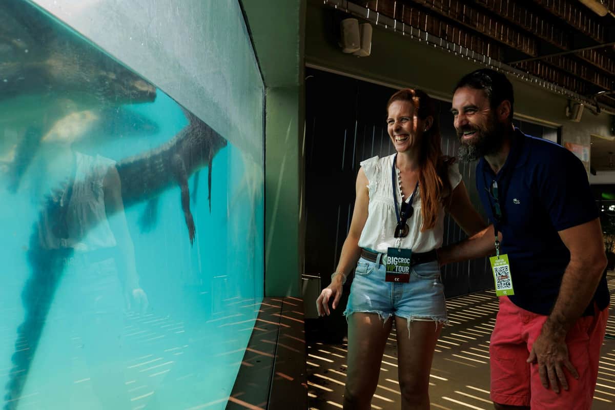 Croc Explorer Combo Two people laughing while looking at an aquarium exhibit, standing in a dimly lit room.
