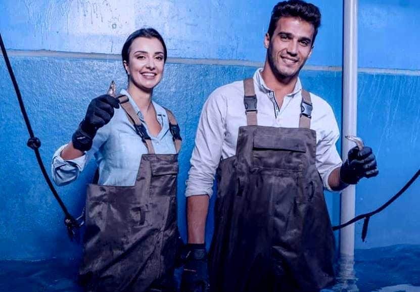 Dubai Aquarium & Underwater Zoo: Entry Ticket + Animal Encounter Two people wearing overalls and gloves, smiling, and holding small fish in a blue room.