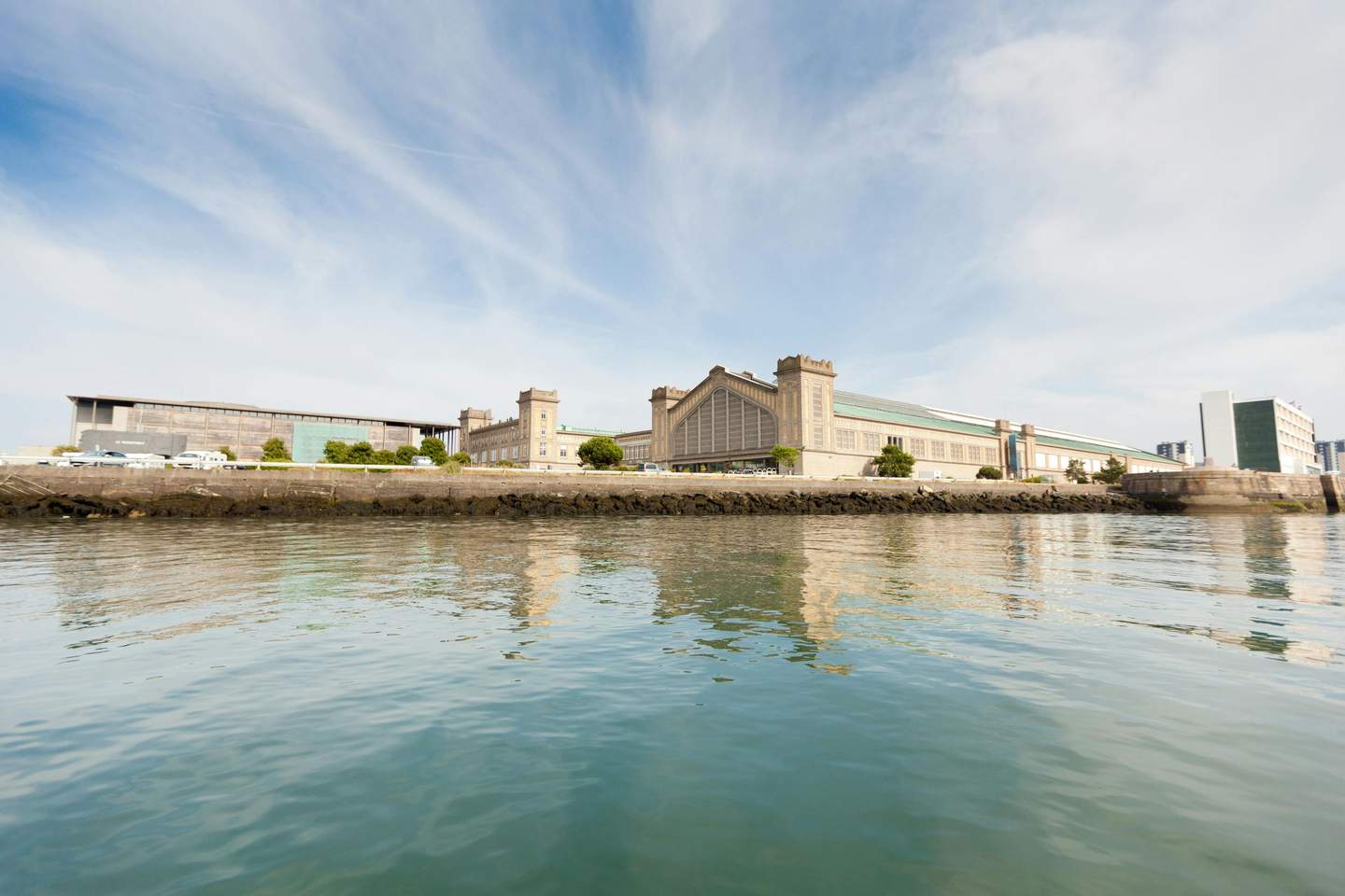 La Cité de la Mer A waterfront view of a large, beige building complex with multiple towers, mirrored in the calm water below.