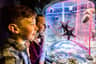 Two children eagerly observe marine life through an aquarium window, with a starfish and sea urchins visible inside.